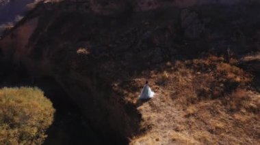 Güney Kazakistan 'daki Aksu Kanyonu' nda yemyeşil elbiseli bir kadın. Peri masalı elbisesi giymiş genç bir kadın kayaların ve dağların arkasında. Dağlık bölgede uzun, havalı elbiseli güzel bir kız.