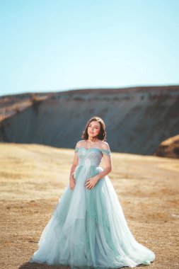 Güney Kazakistan 'daki Aksu Kanyonu' nda yemyeşil, naneli elbiseli bir kadın. Akşam vakti dağların ve kayaların arka planında muhteşem balo elbisesi giyen genç bir kadın. Dağlık bir bölgede, uzun, havadar bir peri elbisesi içinde güzel bir kız.