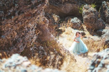 Güney Kazakistan 'daki Aksu Kanyonu' nda yemyeşil, naneli elbiseli bir kadın. Akşam vakti dağların ve kayaların arka planında muhteşem balo elbisesi giyen genç bir kadın. Dağlık bir bölgede, uzun, havadar bir peri elbisesi içinde güzel bir kız.