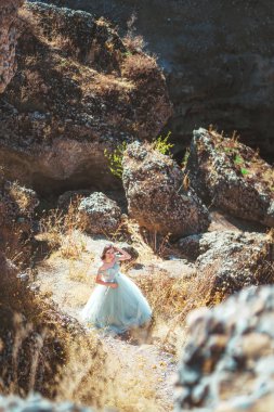 Güney Kazakistan 'daki Aksu Kanyonu' nda yemyeşil, naneli elbiseli bir kadın. Akşam vakti dağların ve kayaların arka planında muhteşem balo elbisesi giyen genç bir kadın. Dağlık bir bölgede, uzun, havadar bir peri elbisesi içinde güzel bir kız.