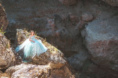 Güney Kazakistan 'daki Aksu Kanyonu' nda yemyeşil, naneli elbiseli bir kadın. Akşam vakti dağların ve kayaların arka planında muhteşem balo elbisesi giyen genç bir kadın. Dağlık bir bölgede, uzun, havadar bir peri elbisesi içinde güzel bir kız.