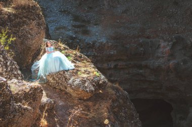Güney Kazakistan 'daki Aksu Kanyonu' nda yemyeşil, naneli elbiseli bir kadın. Akşam vakti dağların ve kayaların arka planında muhteşem balo elbisesi giyen genç bir kadın. Dağlık bir bölgede, uzun, havadar bir peri elbisesi içinde güzel bir kız.