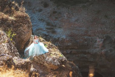 Güney Kazakistan 'daki Aksu Kanyonu' nda yemyeşil, naneli elbiseli bir kadın. Akşam vakti dağların ve kayaların arka planında muhteşem balo elbisesi giyen genç bir kadın. Dağlık bir bölgede, uzun, havadar bir peri elbisesi içinde güzel bir kız.