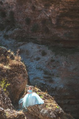 Güney Kazakistan 'daki Aksu Kanyonu' nda yemyeşil, naneli elbiseli bir kadın. Akşam vakti dağların ve kayaların arka planında muhteşem balo elbisesi giyen genç bir kadın. Dağlık bir bölgede, uzun, havadar bir peri elbisesi içinde güzel bir kız.