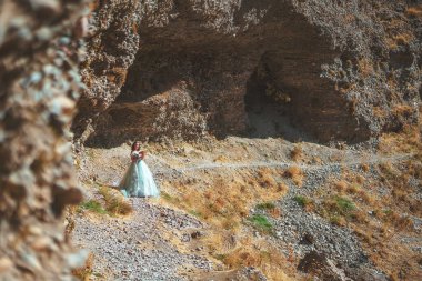 Güney Kazakistan 'daki Aksu Kanyonu' nda yemyeşil, naneli elbiseli bir kadın. Akşam vakti dağların ve kayaların arka planında muhteşem balo elbisesi giyen genç bir kadın. Dağlık bir bölgede, uzun, havadar bir peri elbisesi içinde güzel bir kız.