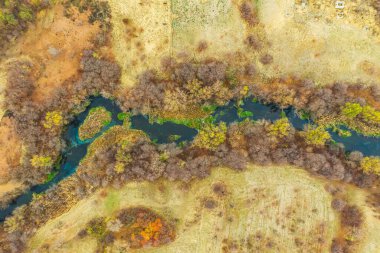 Sonbaharın sonlarında Kazakistan 'ın güneyinde nehir, hava manzaralı. Derin mavi suyu olan güzel küçük bir nehir. Nehir yukarıdan göl manzarasına akar. Bozkırdaki nehir. Nehir dokusu ve kuru sarı otlar.