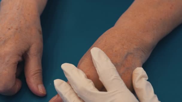 注入手臂静脉的注射物 注射在一个老年妇女的手里 一个戴手套的老妇人和一名医务工作者的手 — 图库视频影像