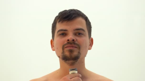 一个年轻人用电动剃须刀刮掉胡子 这家伙的胡子是白色的 面部的毛发摘除 — 图库视频影像