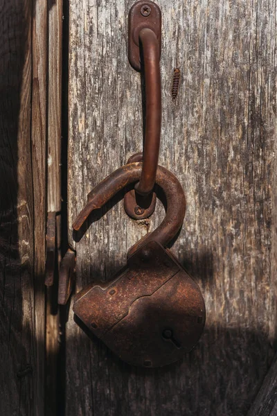 Old rusty barn lock. Open lock on the metal handle of a wooden door. Close-up lock on door