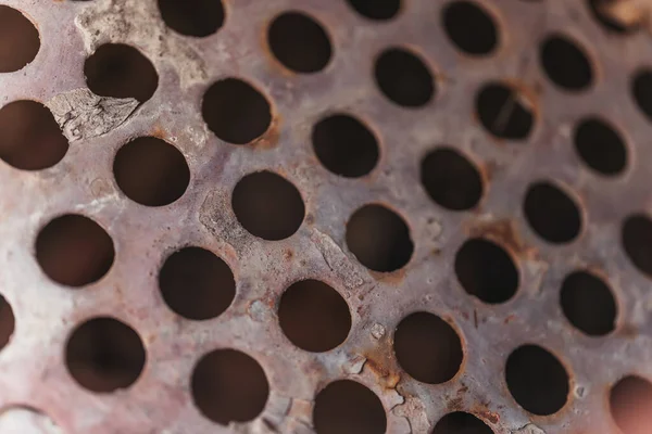 Texture of old rusty perforated metal. Round holes in a metal sheet  closeup. Abstract hole background