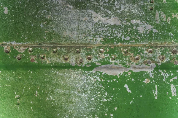 Texture of aged painted metal surface with rivets. Green cracked paint on metal. Old rusty metal rivets and seams