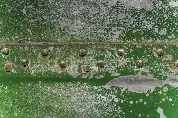 Texture of aged painted metal surface with rivets. Green cracked paint on metal. Old rusty metal rivets and seams