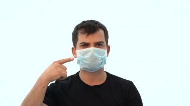 Tıbbi maskeli bir adam. Koruyucu tıbbi yüz maskesi. Covid 19 salgınına karşı yanlış koruma. Yüzündeki maske burnu engellemiyor. Yüz maskesi nasıl takılır?