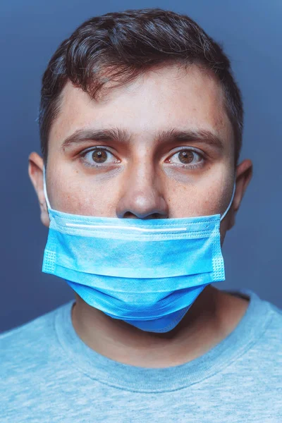 A man in a medical face mask. Wrong wearing of a protective medical face mask. Wrong Virus Protection Covid 19 pandemic. The mask on the face does not block the nose. Face mask on a young man