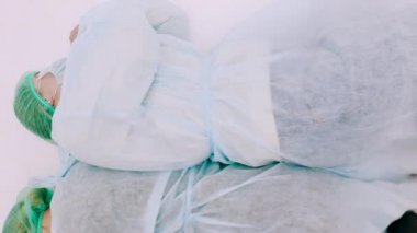 Koruyucu takım elbiseli ve yüz maskeli iki kadın. Genç kızlar koruyucu sağlık önlükleri, kepleri ve maskeleriyle beyaz zeminde yatıyorlar. Grip salgını trajedisi