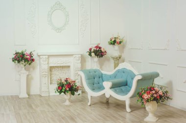 Beyaz ışıklı odada klasik tarzda mavi bir kanepe. Fotoğraf stüdyosundaki klasik Empire Hall 'un tasarımı. Oturma odasında yapay çiçekler var.