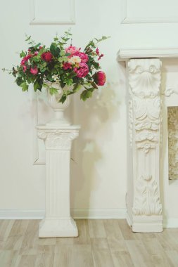 Yapay pembe şakayık buketi, okaliptüs ve beyaz vazoda ortancalar. Alçılı beyaz bir sütundaki çiçekli vazo. Stüdyoda bahar fotoğraf bölgesi