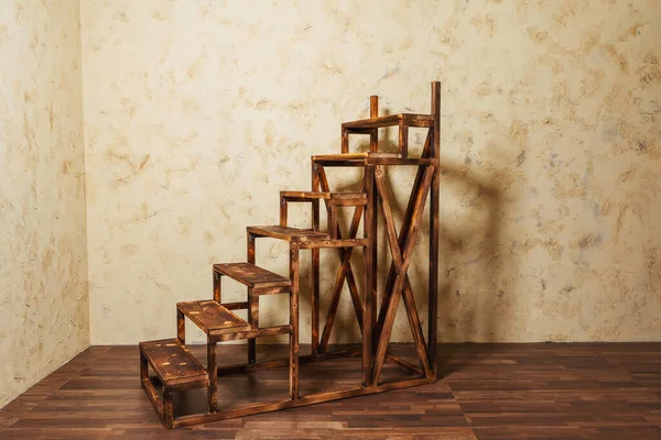 Wooden decorative staircase against a yellow wall. Stairs in the photo Studio . Wooden Stepladder