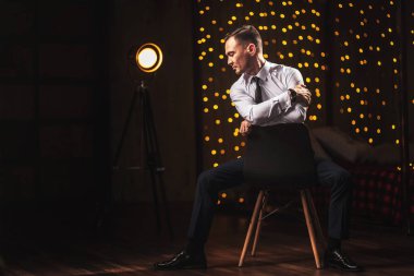 Bokeh çelenklerinin arka planında beyaz gömlekli bir adamın portresi. Çatı katındaki odada bir adamın güzel, şık portresi. Noel çelenklerinin arkasında genç bir Asyalı beyefendi.