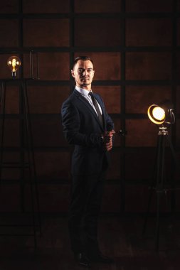 Siyah ahşap arka planda beyaz gömlekli ve takım elbiseli adamın portresi. Çatı katı tarzı bir odada güzel şık erkek portresi. Genç yakışıklı Asyalı işadamı