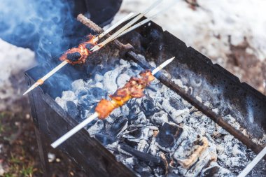 Barbekü ile kamp yapmak. Izgarada et şiş kebap olan şişi yapıştır. Kış pikniğinde dumanın içinde barbekü.