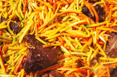 Dışarıda piknikte büyük bir kazanda pilav pişirmek. Özbek bayram pilavı pişiriyorum. Havuç ve et bir kazanda pilav için büyük bir kazanda canlı ateşte pirinçle birlikte.