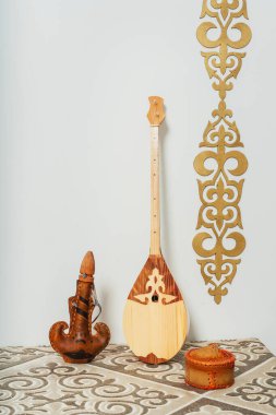 Beyaz arka planda Kazak ulusal müzik aleti dombra. Ulusal Kazak dekor altın süslemeleri ve ev eşyaları. Kazak Kırgız etnik geçmişi