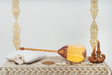 Beyaz arka planda Kazak ulusal müzik aleti dombra. Ulusal Kazak dekor altın süslemeleri ve ev eşyaları. Kazak Kırgız etnik geçmişi
