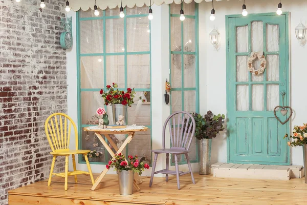 家の夏のポーチに庭のテーブルと椅子 レトロな電球のガーランドと夏のテラス 写真スタジオで春の装飾が施された美しいポーチ — ストック写真