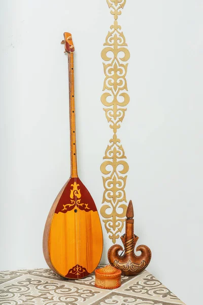 Kazakh national musical instrument dombra on a white background. National Kazakh decor gold ornaments and household items. Kazakh Kyrgyz ethnic background