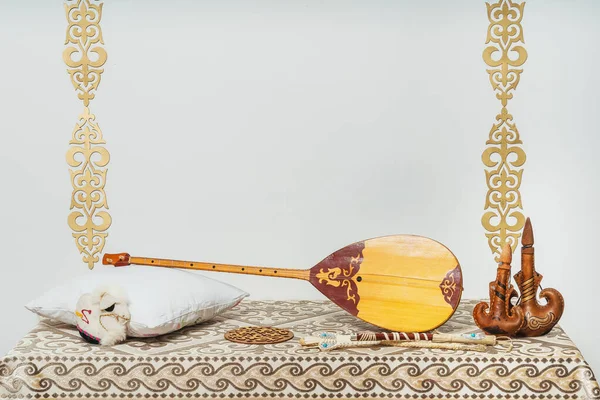 Beyaz arka planda Kazak ulusal müzik aleti dombra. Ulusal Kazak dekor altın süslemeleri ve ev eşyaları. Kazak Kırgız etnik geçmişi