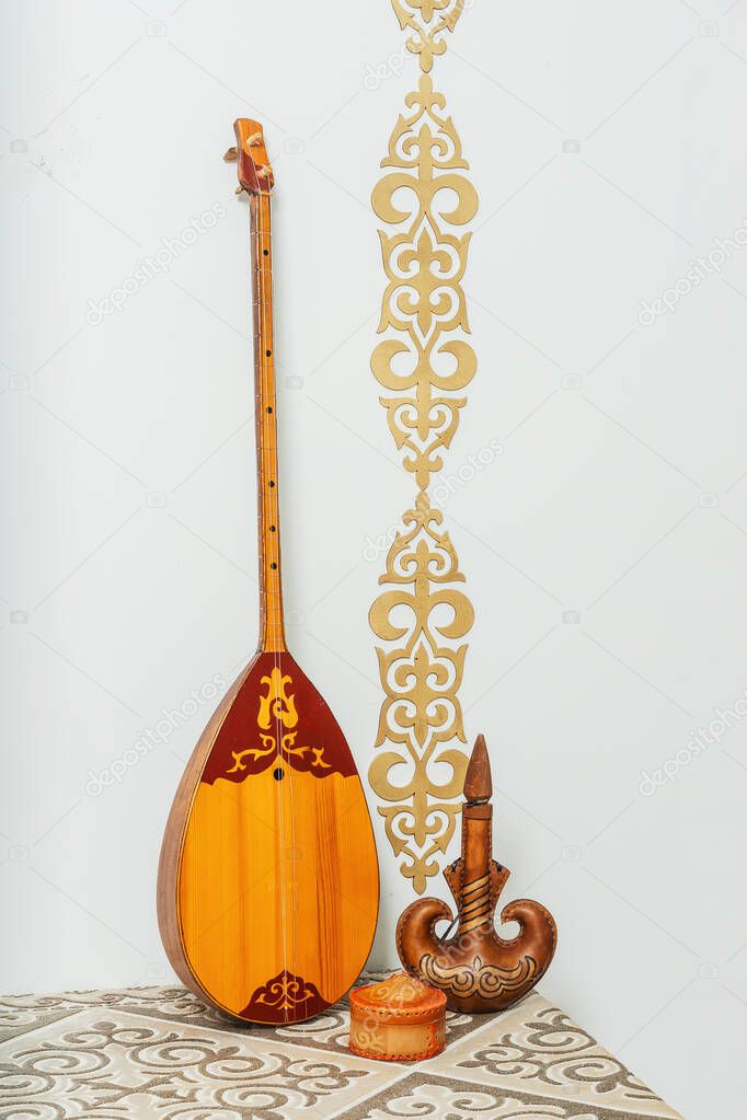 Kazakh national musical instrument dombra on a white background. National Kazakh decor gold ornaments and household items. Kazakh Kyrgyz ethnic background