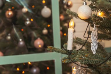 Noel ağacında mum şeklinde bir çelenk. Noel ağacında beyaz süsleme topları, yakın plan. Sahte Noel ağacı