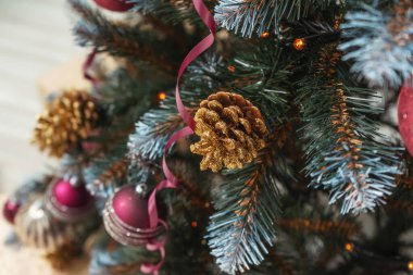 Pembe altın kestane rengi çelenkler suni Noel ağacı süslemelerine yakın duruyor. Noel ağacında altın renkli gümüş renkli pullar. Noel ağacının dokusu