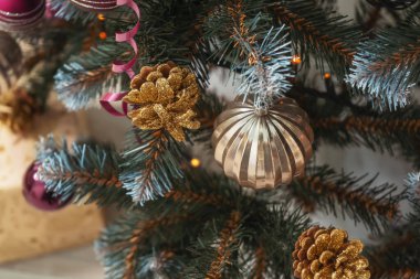 Pembe altın kestane rengi çelenkler suni Noel ağacı süslemelerine yakın duruyor. Noel ağacında altın renkli gümüş renkli pullar. Noel ağacının dokusu