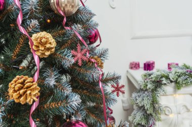 Pembe altın kestane rengi çelenkler suni Noel ağacı süslemelerine yakın duruyor. Noel ağacında altın renkli gümüş renkli pullar. Noel ağacının dokusu