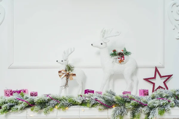 暖炉の上に白いクリスマス鹿の二人の姿 鹿やモミの枝で暖炉のマントルピースの装飾 スタッコ成形クローズアップと白い暖炉 — ストック写真