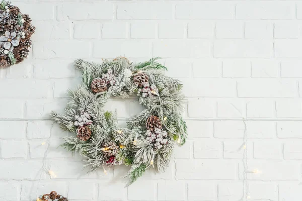 Spruce artificial wreath on a brick white wall. Christmas decor in the room in gold and blue style. Metal gold candlesticks with New year decor