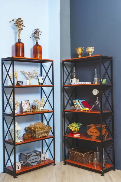 Metal wooden shelves near the blue wall in the interior. Cabinets shelves with autumn decorations. Interior decoration with cozy details