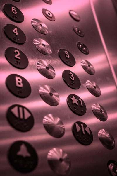 Elevator Buttons / Close up of elevator buttons, metallic with a red tint.