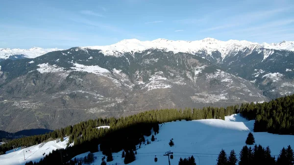Воздушная зимняя сцена альпийских снежных вершин и тёмных еловых лесов в снегу — стоковое фото