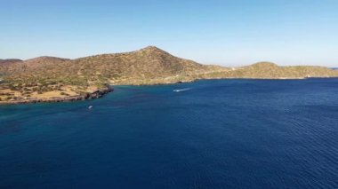 Koyu mavi bir denizde hız yapan bir motorlu teknenin hava görüntüsü. Spinalonga Adası, Girit, Yunanistan