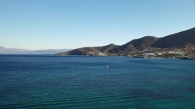 Koyu mavi bir denizde hız yapan bir motorlu teknenin hava görüntüsü. Spinalonga Adası, Girit, Yunanistan