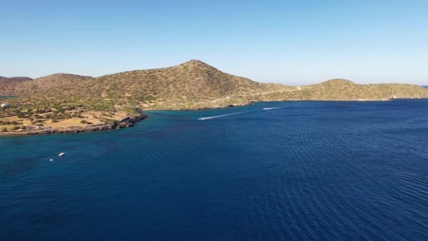 Légi kilátás egy motorcsónak egy mély kék színű tenger. Spinalonga-sziget, Kréta, Görögország — Stock videók