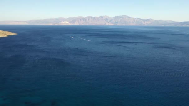 Vista aérea de un barco de motos acuáticas en un mar de color azul profundo. Isla Spinalonga, Creta, Grecia — Vídeos de Stock