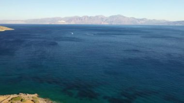 Koyu mavi bir denizde bir jet ski teknesinin hava görüntüsü. Spinalonga Adası, Girit, Yunanistan