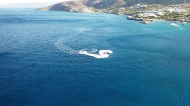 Koyu mavi bir denizde bir jet ski teknesinin hava görüntüsü. Spinalonga Adası, Girit, Yunanistan