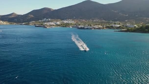 Flygfoto av en motorbåt som bogserar en vattenskidåkare. Elounda, Kreta, Grekland — Stockvideo