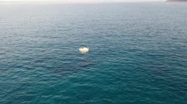 Koyu mavi bir denizde, motorlu bir teknenin havadan görünüşü. Kolokitha Adası, Girit, Yunanistan
