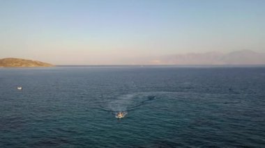 Koyu mavi bir denizde, motorlu bir teknenin havadan görünüşü. Kolokitha Adası, Girit, Yunanistan